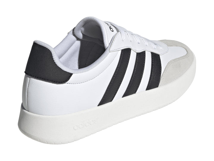 Tenis Adidas blancos con tres franjas negras laterales y punta gris.