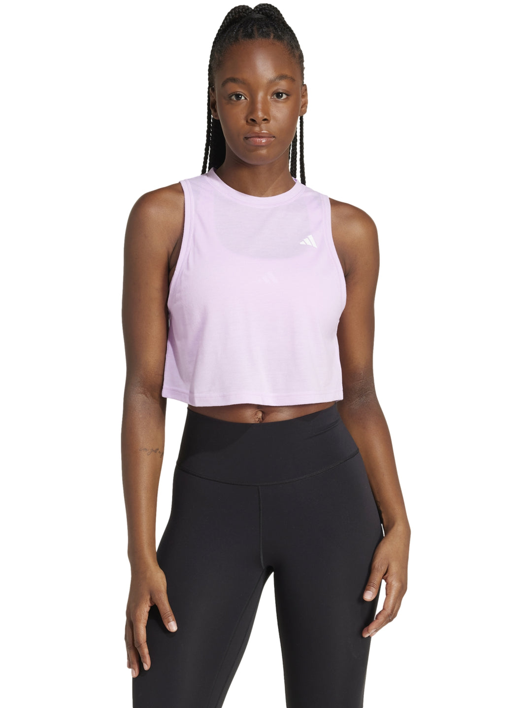Mujer vistiendo una camiseta deportiva Adidas corta y holgada en color lila claro con cuello redondo.
