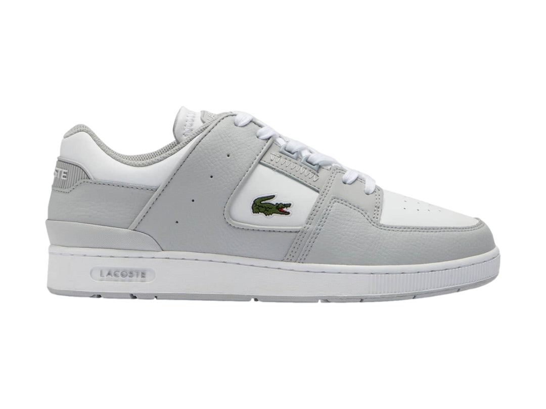 Tenis Lacoste Court Cage en color gris claro y blanco con logotipo de cocodrilo verde.