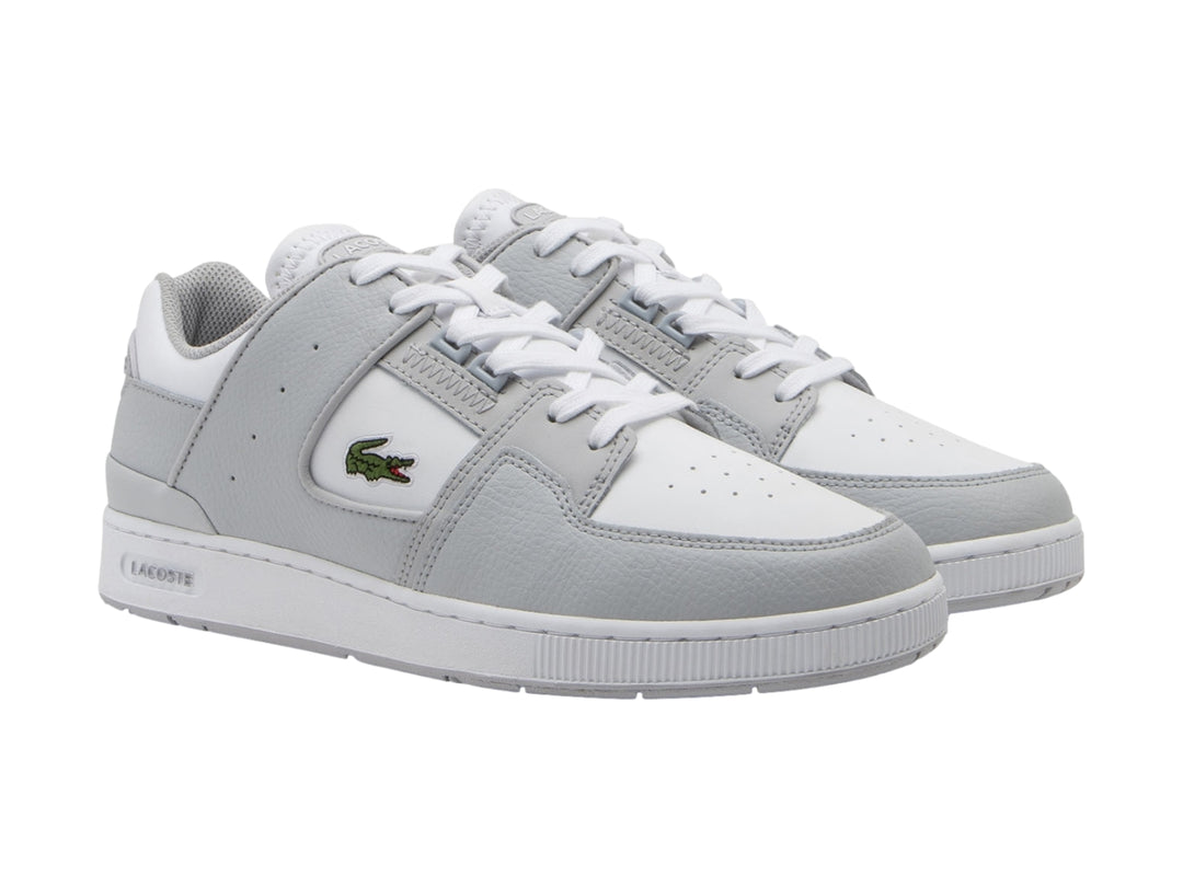 Tenis Lacoste Court Cage en color gris claro y blanco con logotipo de cocodrilo verde.