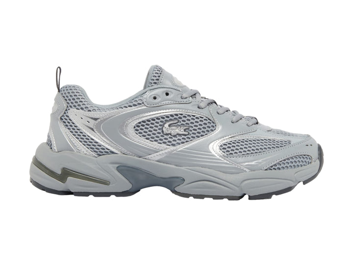 Tenis deportivos Lacoste color gris y plateado con suela gruesa y detalles de malla.