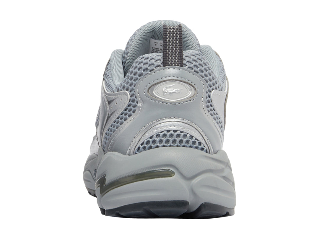 Tenis deportivos Lacoste color gris y plateado con suela gruesa y detalles de malla.