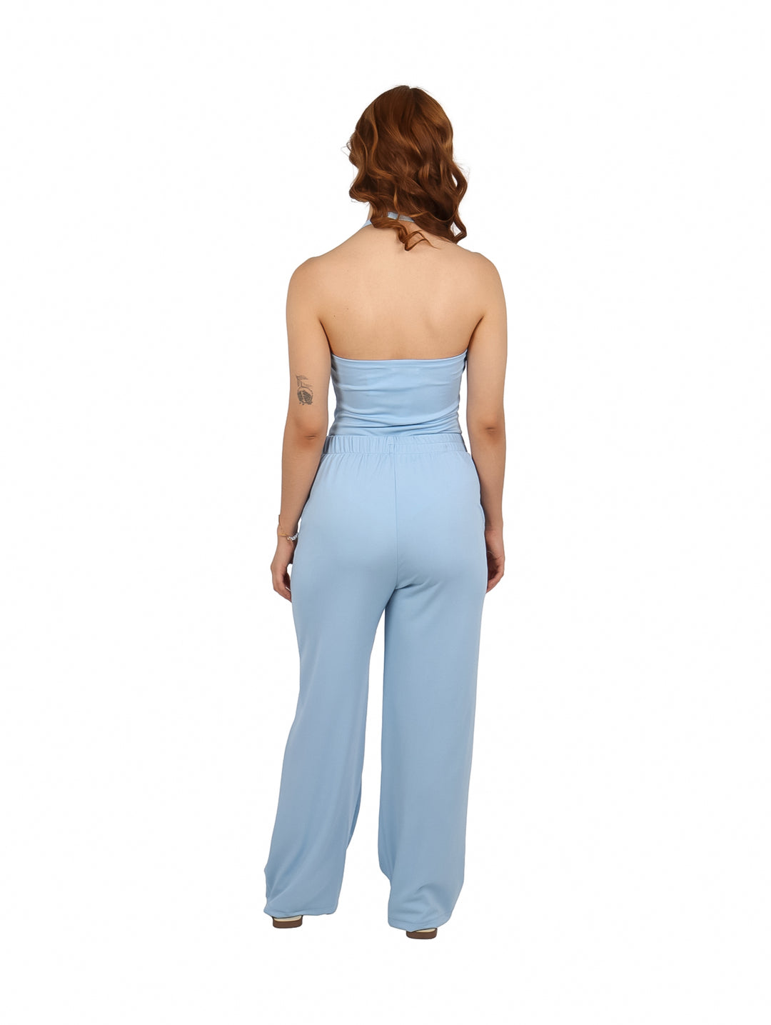 Mujer vistiendo un conjunto azul de dos piezas con top halter y pantalones anchos con detalles de conchas.