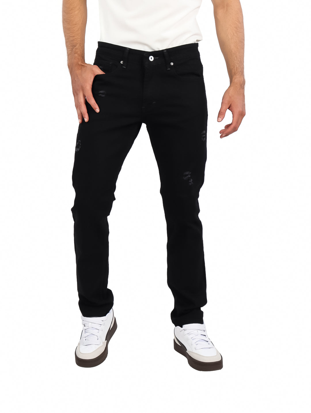 Hombre vistiendo jeans negros de corte slim con detalles desgastados y calzado blanco.