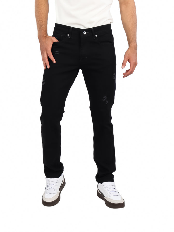 Hombre vistiendo jeans negros de corte slim con detalles desgastados y calzado blanco.