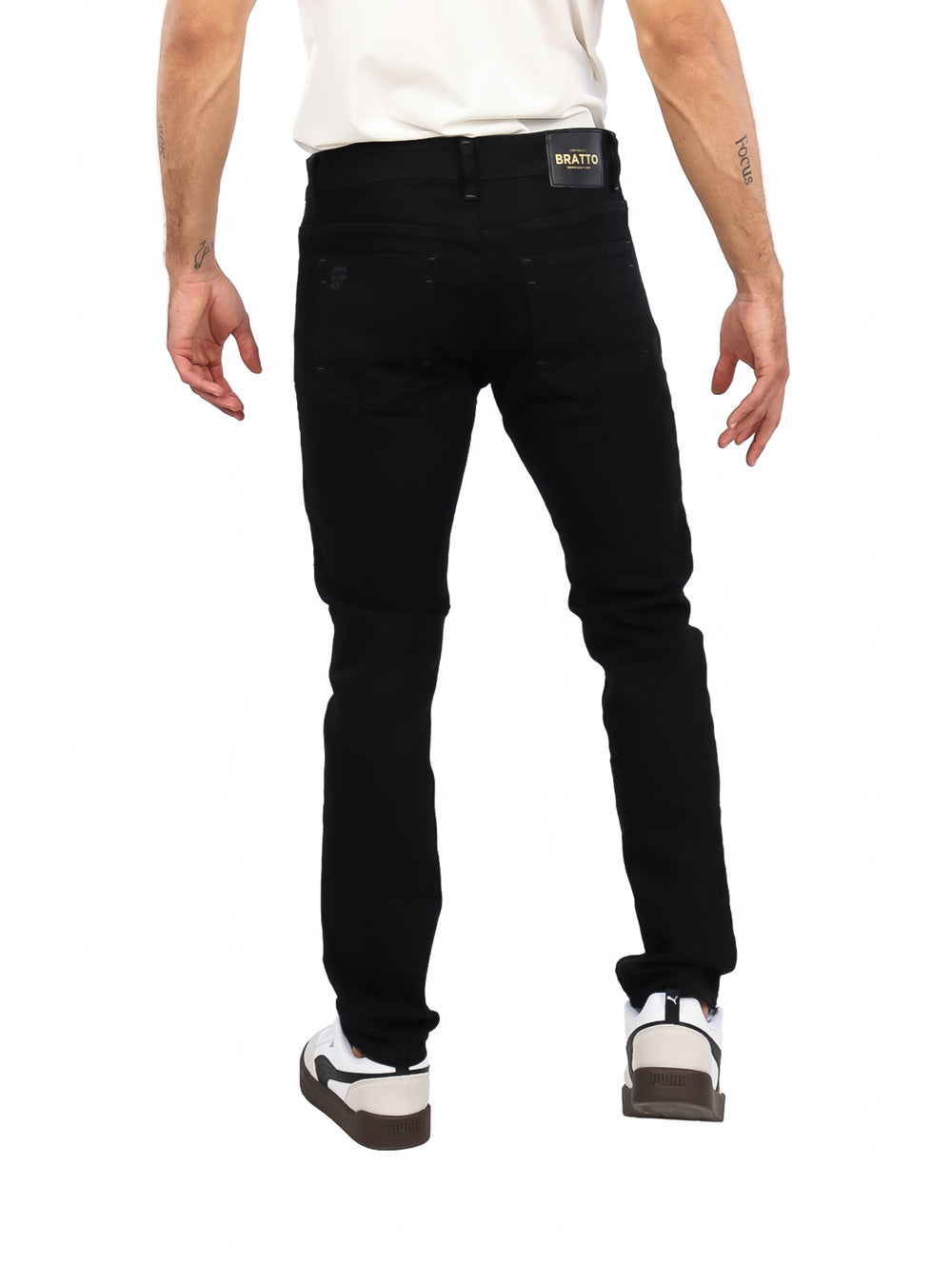 Hombre vistiendo jeans negros de corte slim con detalles desgastados y calzado blanco.