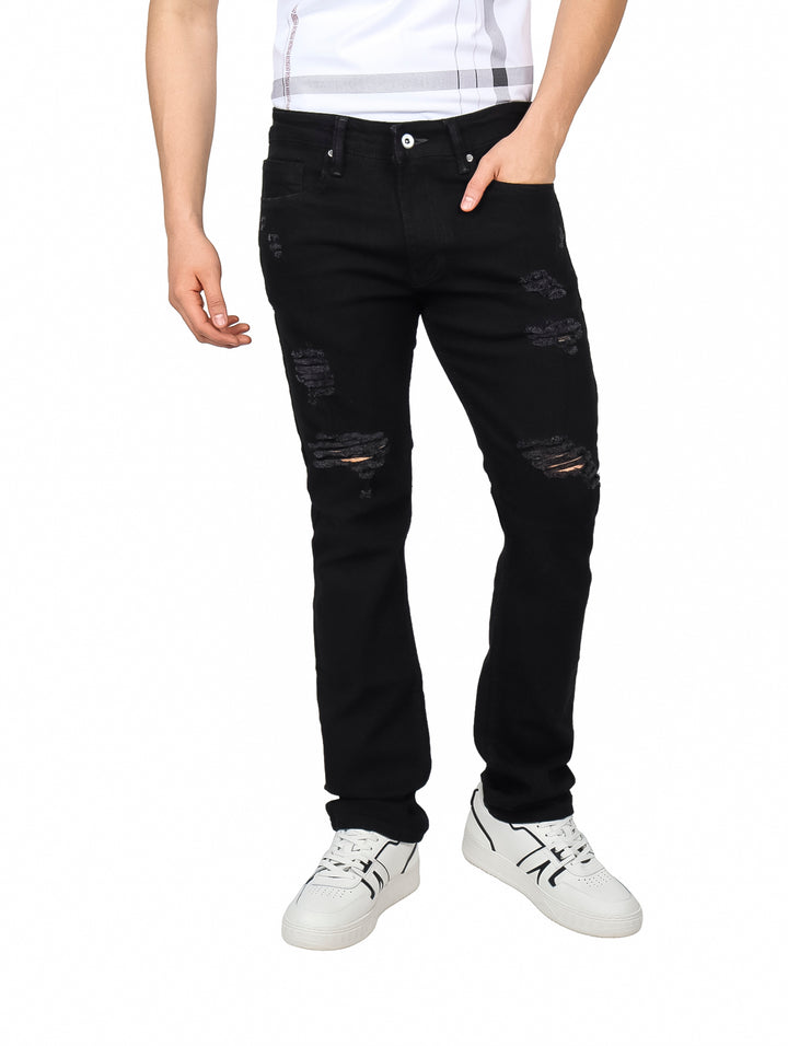 Hombre vistiendo jeans negros con detalles de destrucción en las rodillas y muslos.