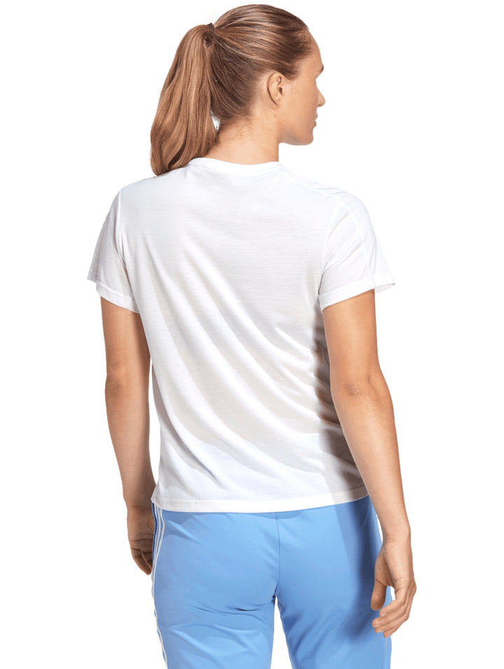 Mujer vistiendo una camiseta deportiva blanca de manga corta con logotipo pequeño de Adidas en el pecho.