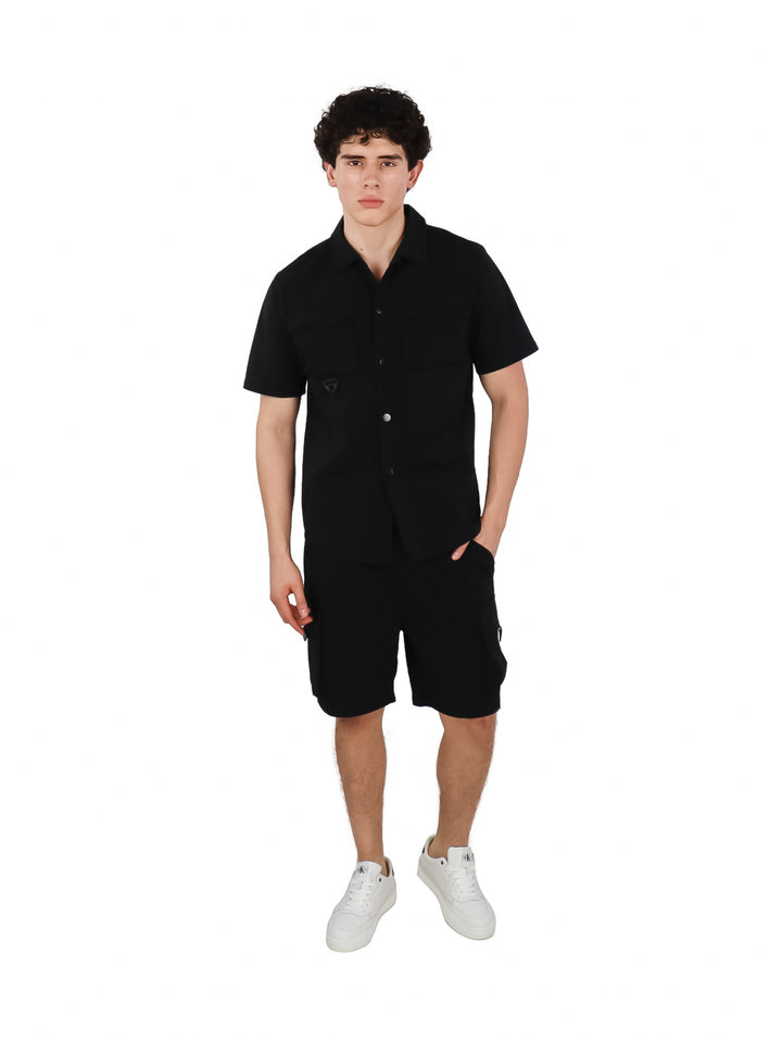 Hombre vistiendo un conjunto casual de camisa y shorts color negro.