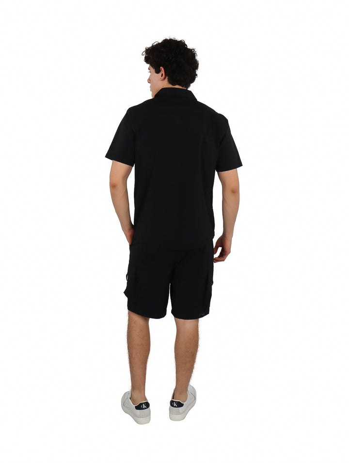 Hombre vistiendo un conjunto casual de camisa y shorts color negro.