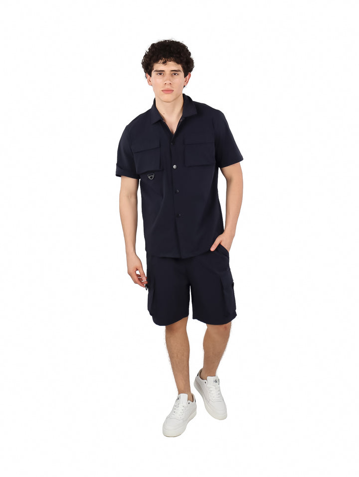 Hombre vistiendo un conjunto de camisa y shorts color azul marino.