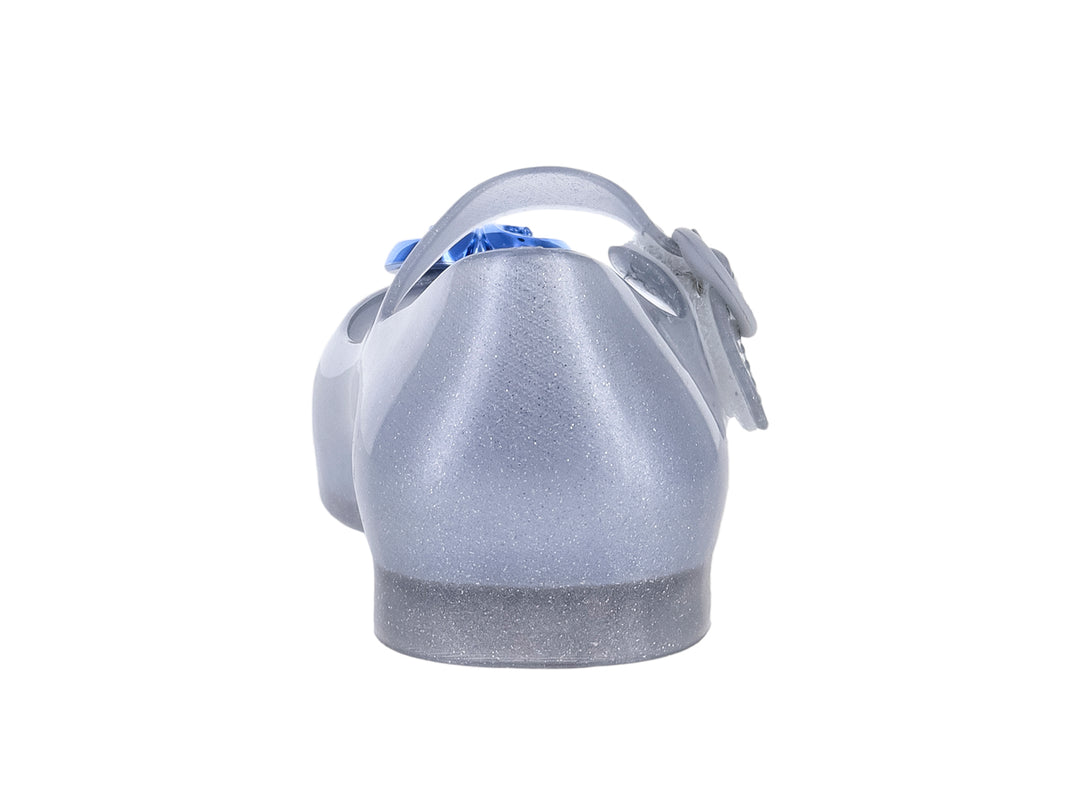 Zapato plateado con glitter para niña, correa ajustable y detalle de corazón azul en la punta.