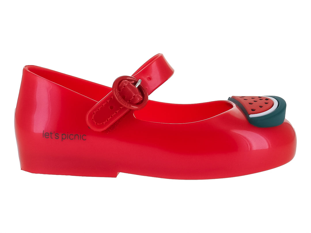 Zapato rojo brillante de plástico con correa y detalle de rebanada de sandía en la punta.
