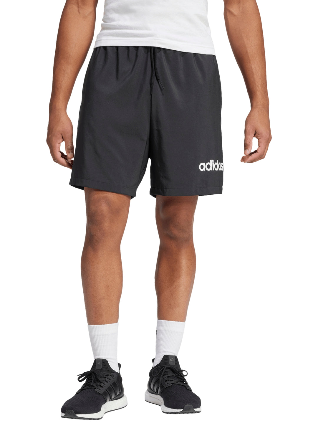Hombre vistiendo shorts deportivos negros de Adidas con logo blanco en la pierna izquierda.