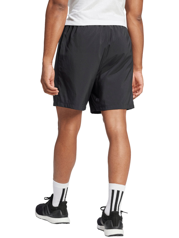 Hombre vistiendo shorts deportivos negros de Adidas con logo blanco en la pierna izquierda.