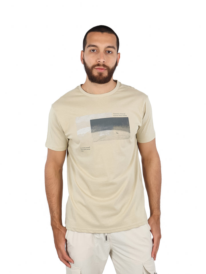 Hombre vistiendo una camiseta beige de manga corta con un estampado gráfico en el pecho.