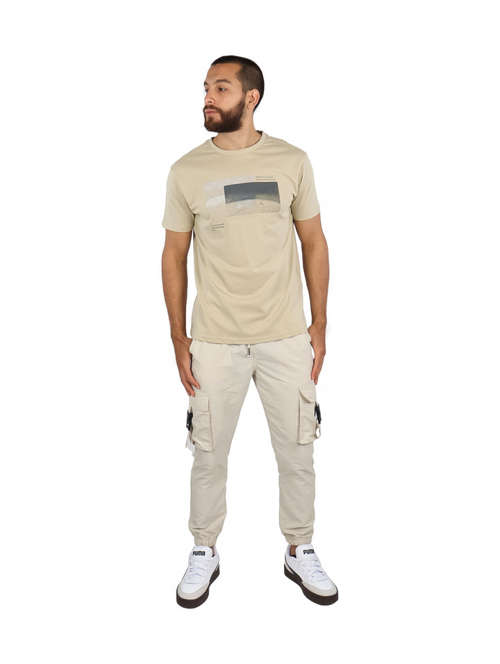 Hombre vistiendo una camiseta beige de manga corta con un estampado gráfico en el pecho.