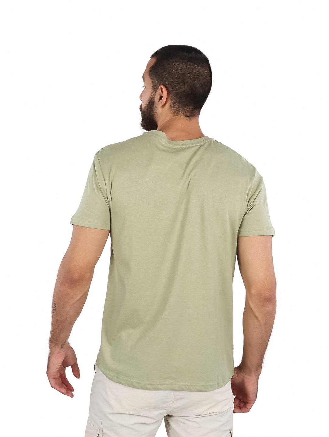 Hombre vistiendo una camiseta de manga corta color verde claro con un estampado frontal de palmeras en tonos azul y blanco.