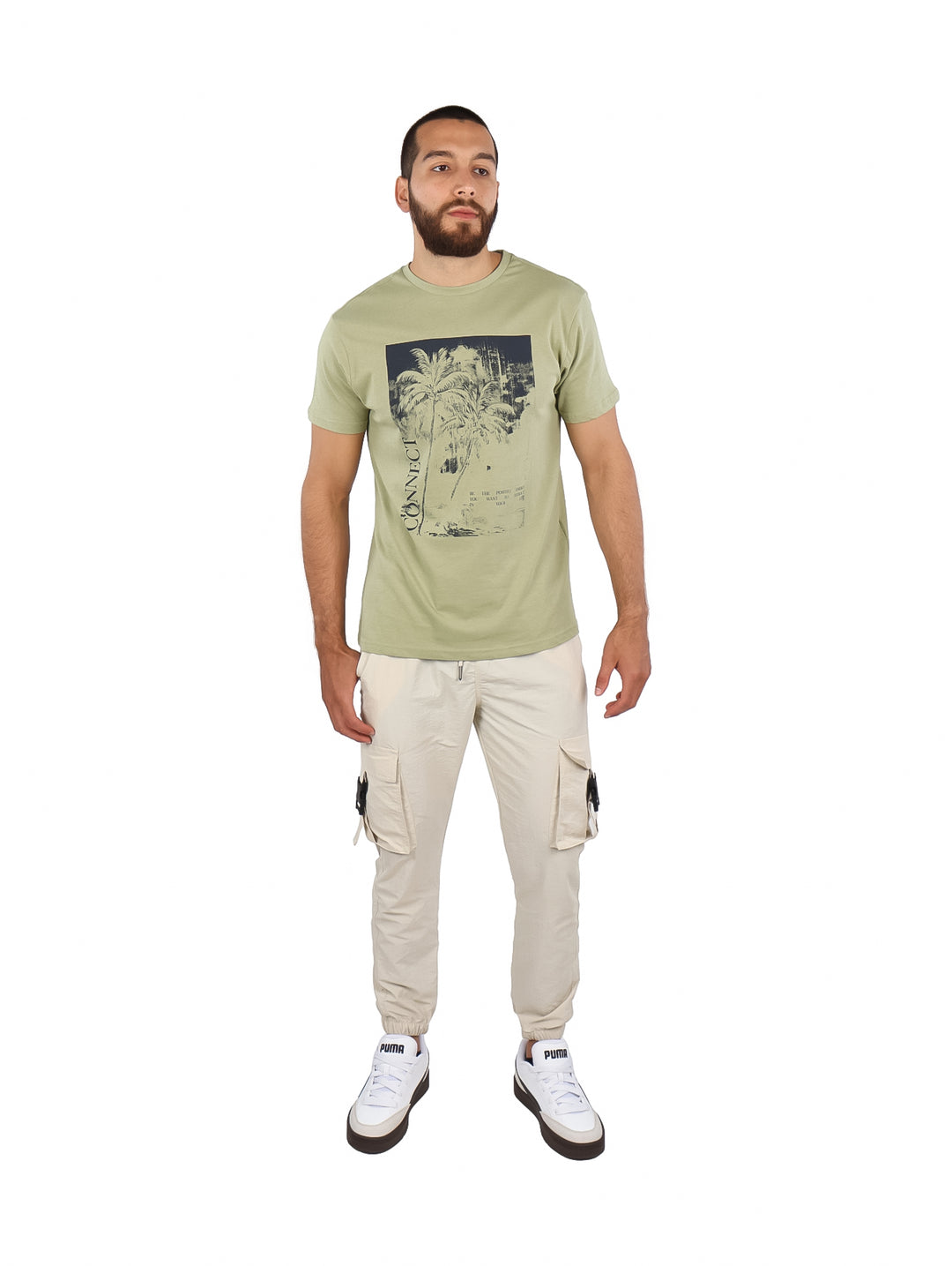 Hombre vistiendo una camiseta de manga corta color verde claro con un estampado frontal de palmeras en tonos azul y blanco.
