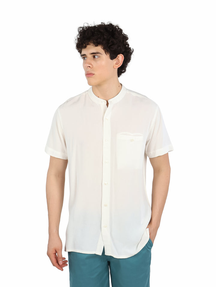 Hombre vistiendo una camisa blanca de manga corta con cuello mao y bolsillo frontal.