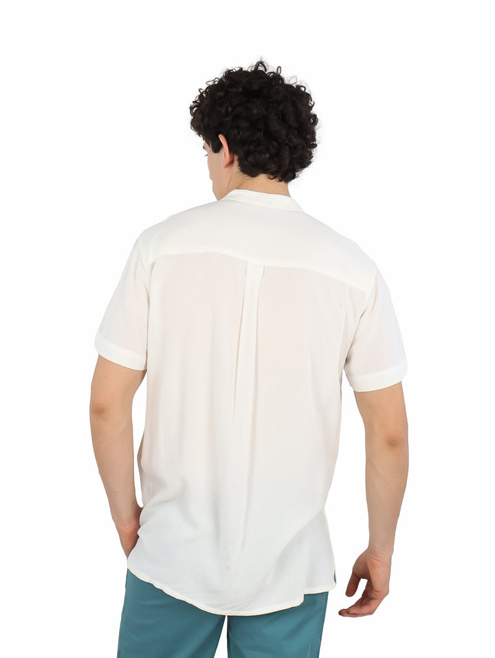 Hombre vistiendo una camisa blanca de manga corta con cuello mao y bolsillo frontal.