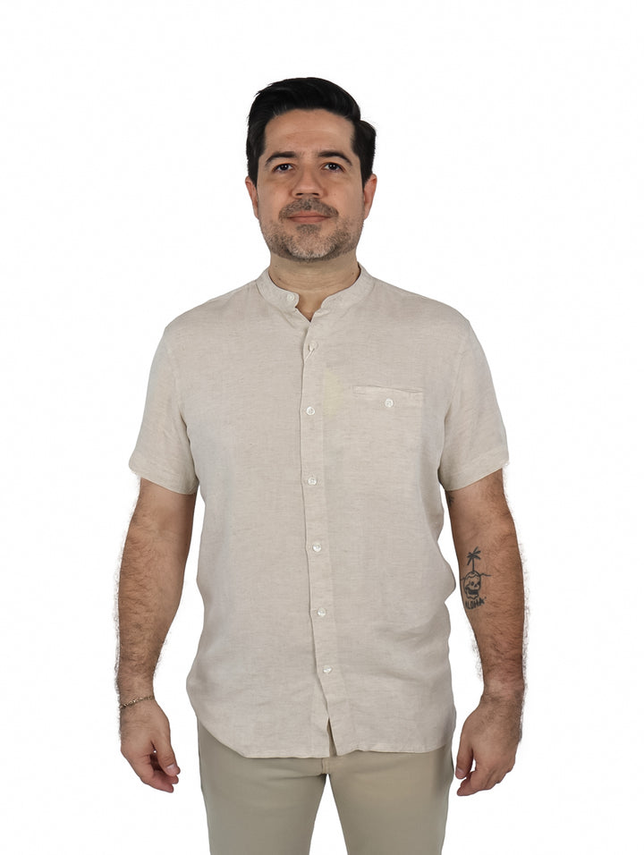 Hombre vistiendo una camisa de manga corta color beige con cuello mao y un bolsillo frontal.