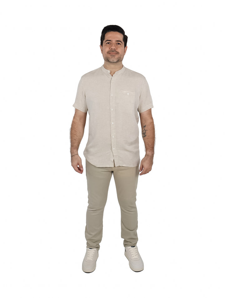 Hombre vistiendo una camisa de manga corta color beige con cuello mao y un bolsillo frontal.