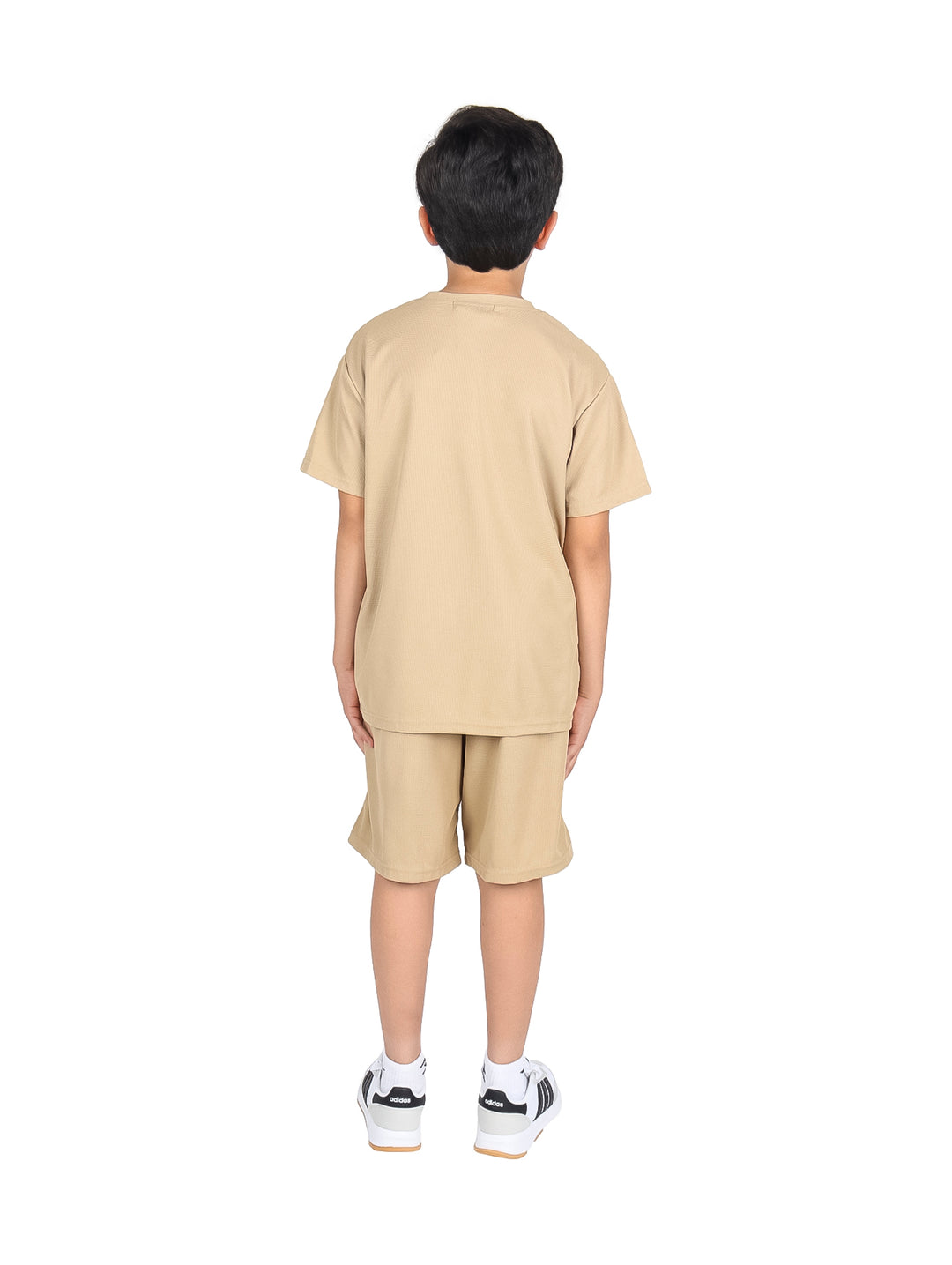Niño vistiendo un conjunto de camiseta y short color beige.