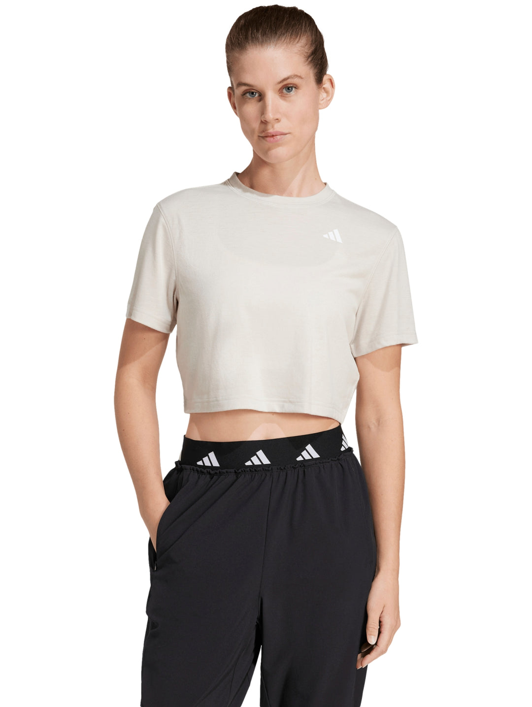 Mujer vistiendo camiseta de entrenamiento Adidas color beige con corte boxy y cuello redondo.