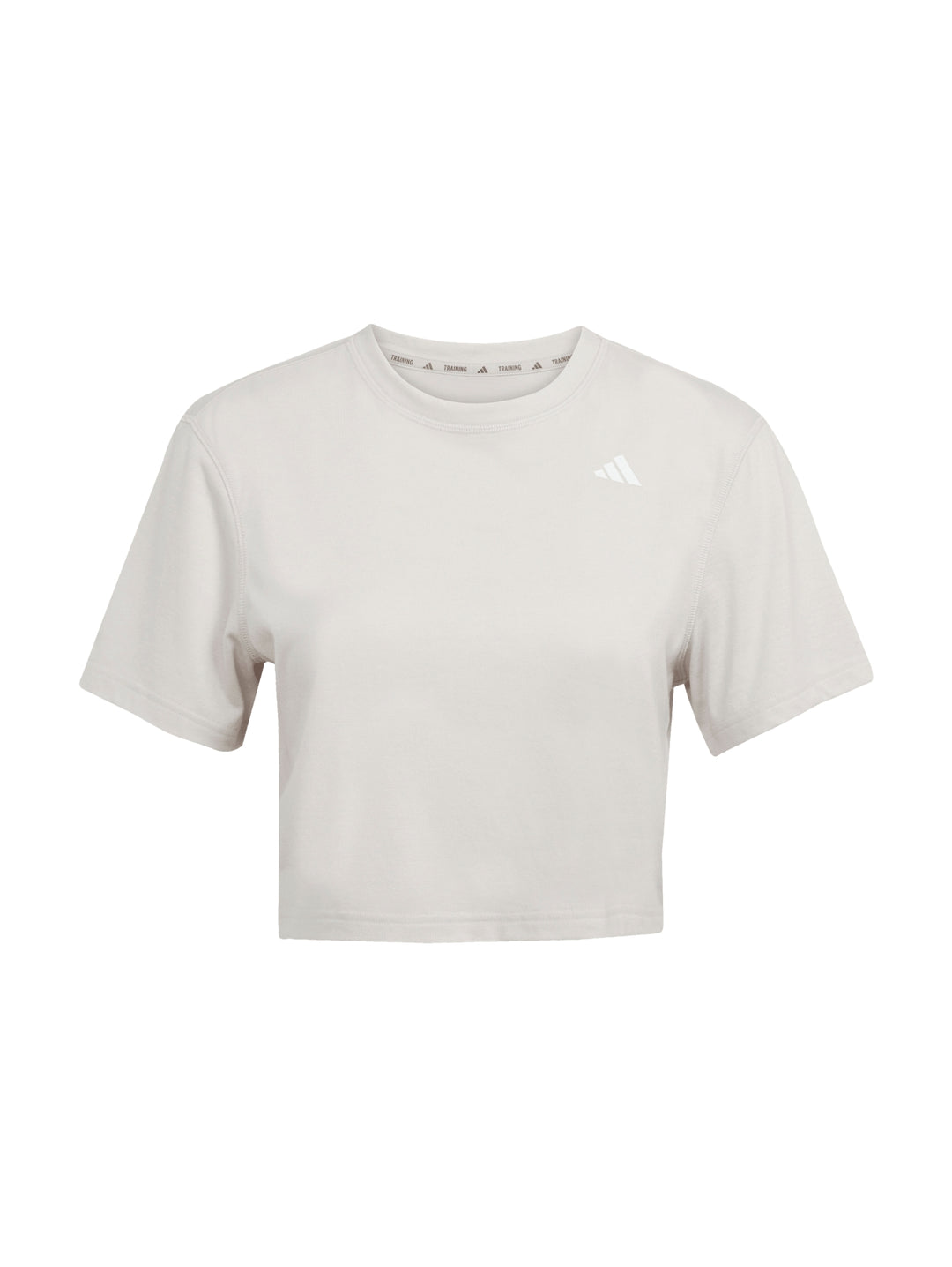 Mujer vistiendo camiseta de entrenamiento Adidas color beige con corte boxy y cuello redondo.