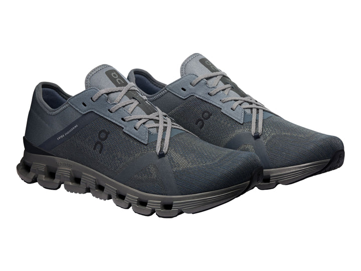 Tenis deportivos On Cloud X 4 AD en color negro y gris oscuro con suela segmentada característica.