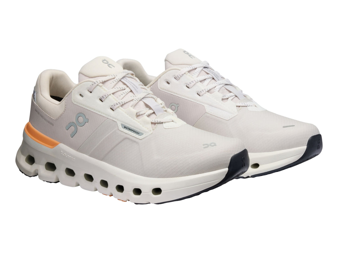 Tenis deportivos On Cloudrunner 2 WP color gris con detalles naranja y suela blanca con cavidades.