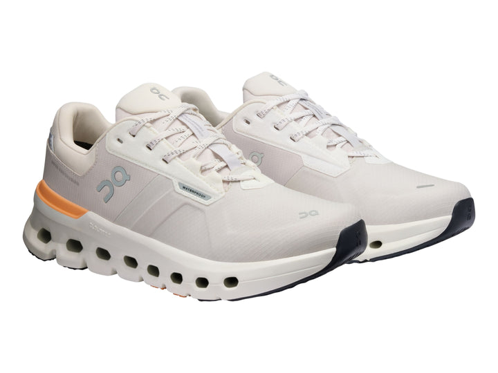 Tenis deportivos On Cloudrunner 2 WP color gris con detalles naranja y suela blanca con cavidades.
