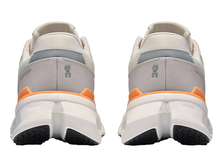 Tenis deportivos On Cloudrunner 2 WP color gris con detalles naranja y suela blanca con cavidades.