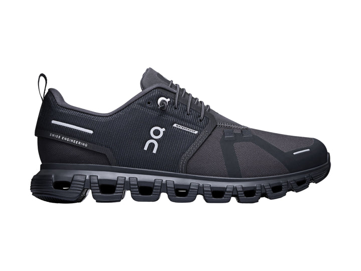 Tenis deportivos On Cloud color negro con suela amortiguada característica y detalles en blanco.