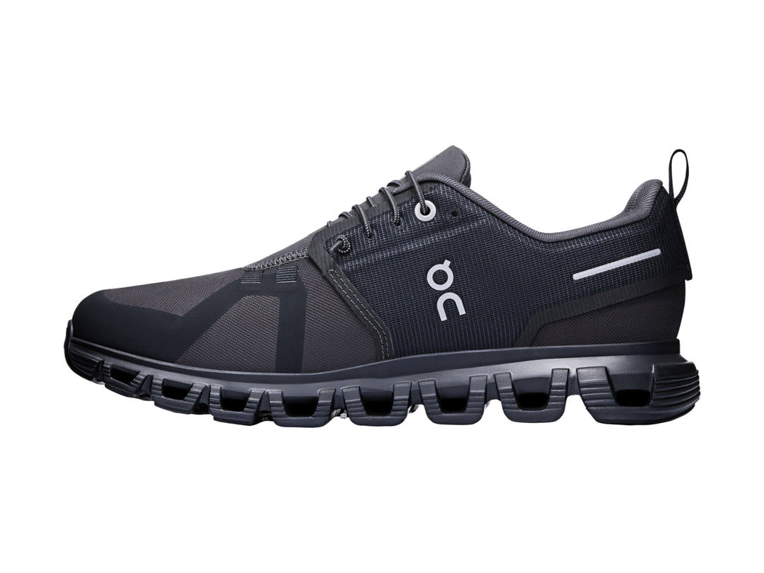 Tenis deportivos On Cloud color negro con suela amortiguada característica y detalles en blanco.