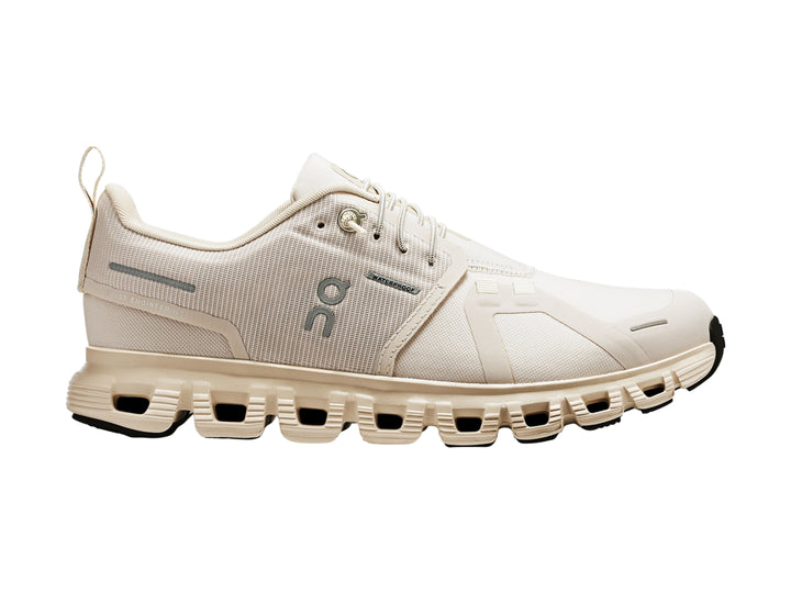 Tenis deportivos On Cloud color crema con suela amortiguada y detalles en gris.
