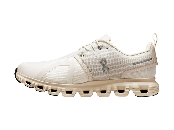 Tenis deportivos On Cloud color crema con suela amortiguada y detalles en gris.