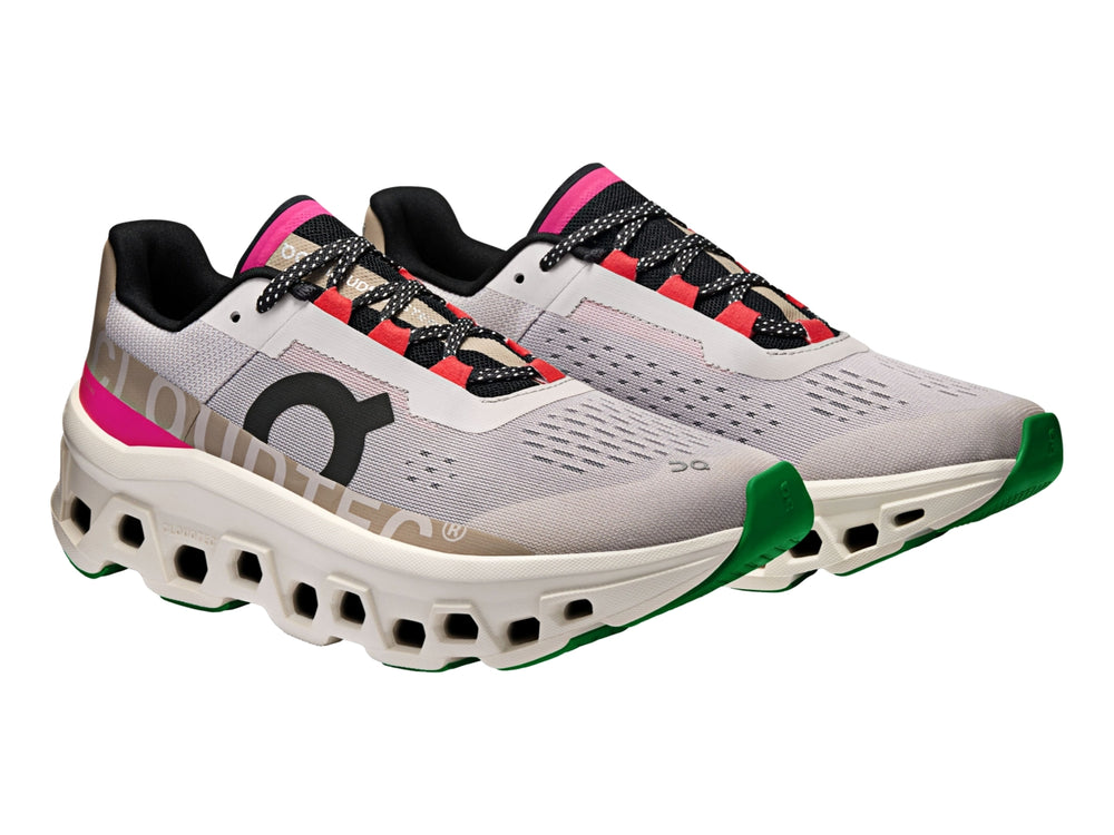 Tenis deportivos On Cloudmonster en color plata y marfil con detalles en rosa y negro.