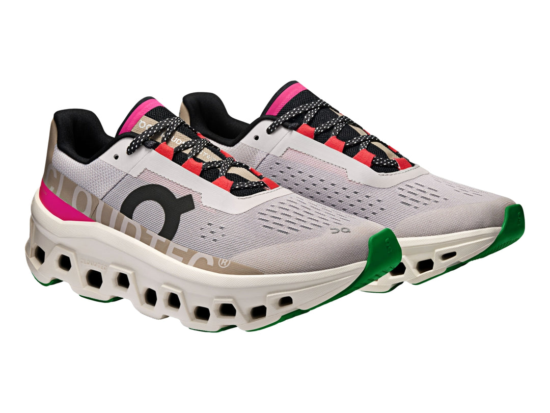 Tenis deportivos On Cloudmonster en color plata y marfil con detalles en rosa y negro.