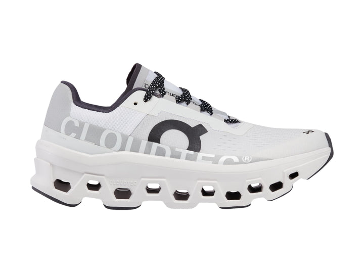 Tenis deportivos On Cloudmonster color blanco con detalles negros y suela amortiguada.