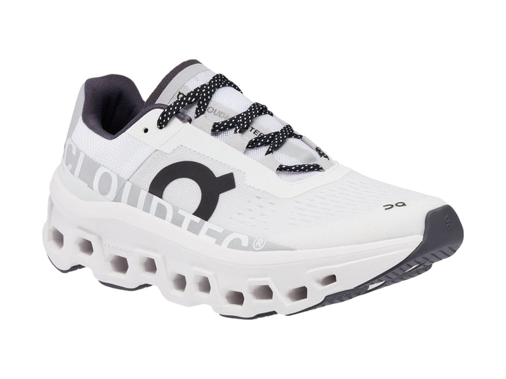 Tenis deportivos On Cloudmonster color blanco con detalles negros y suela amortiguada.