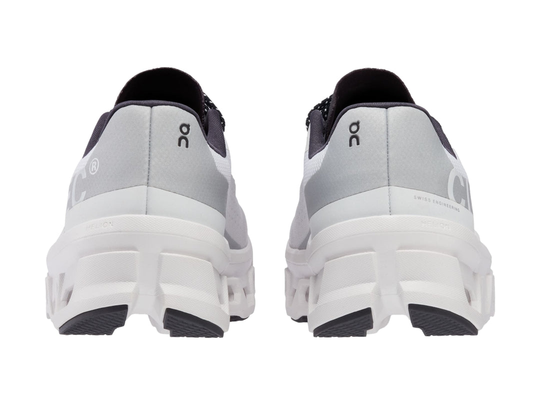 Tenis deportivos On Cloudmonster color blanco con detalles negros y suela amortiguada.