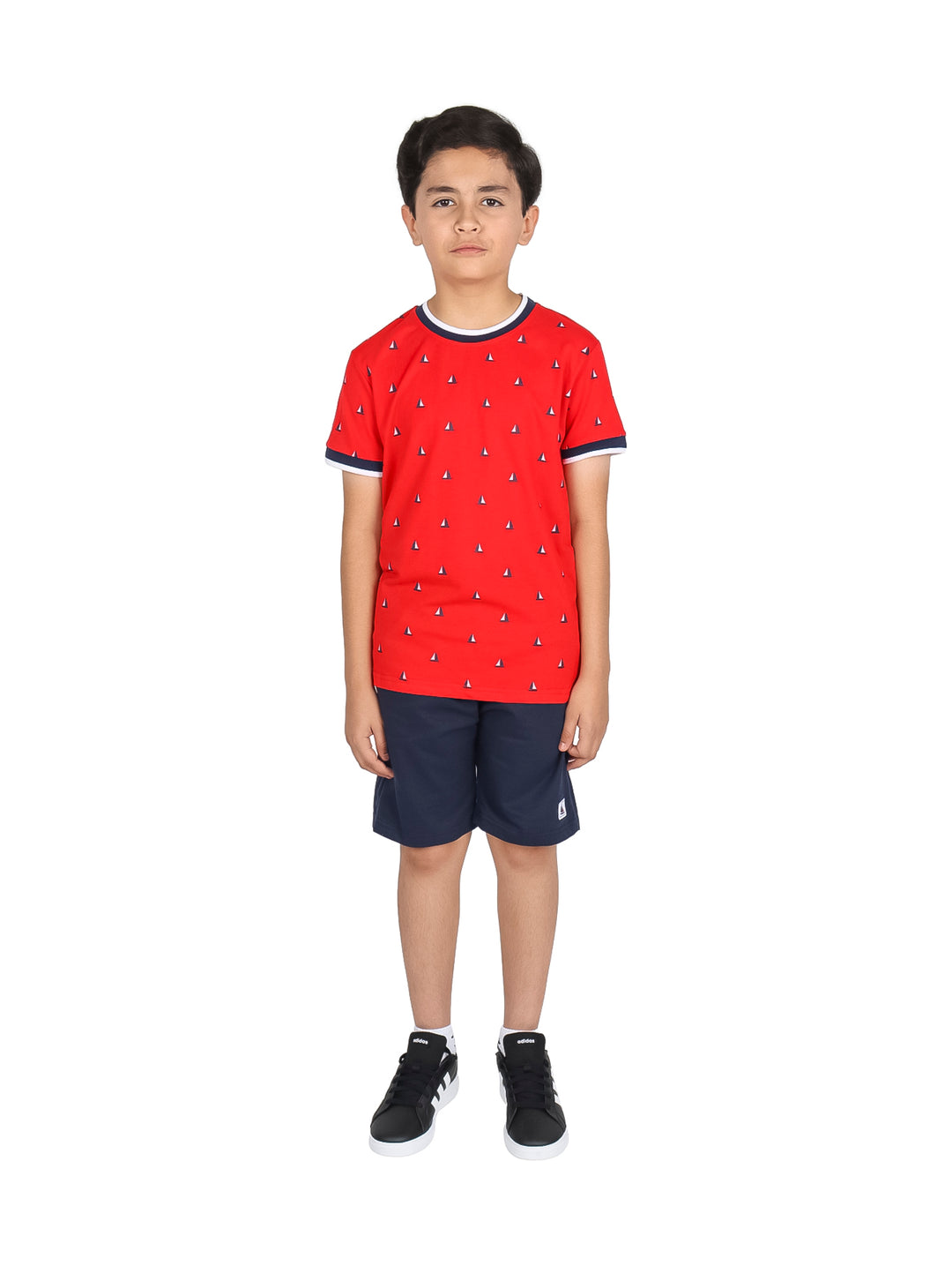 Niño vistiendo un conjunto de camiseta roja con estampado y short azul marino.