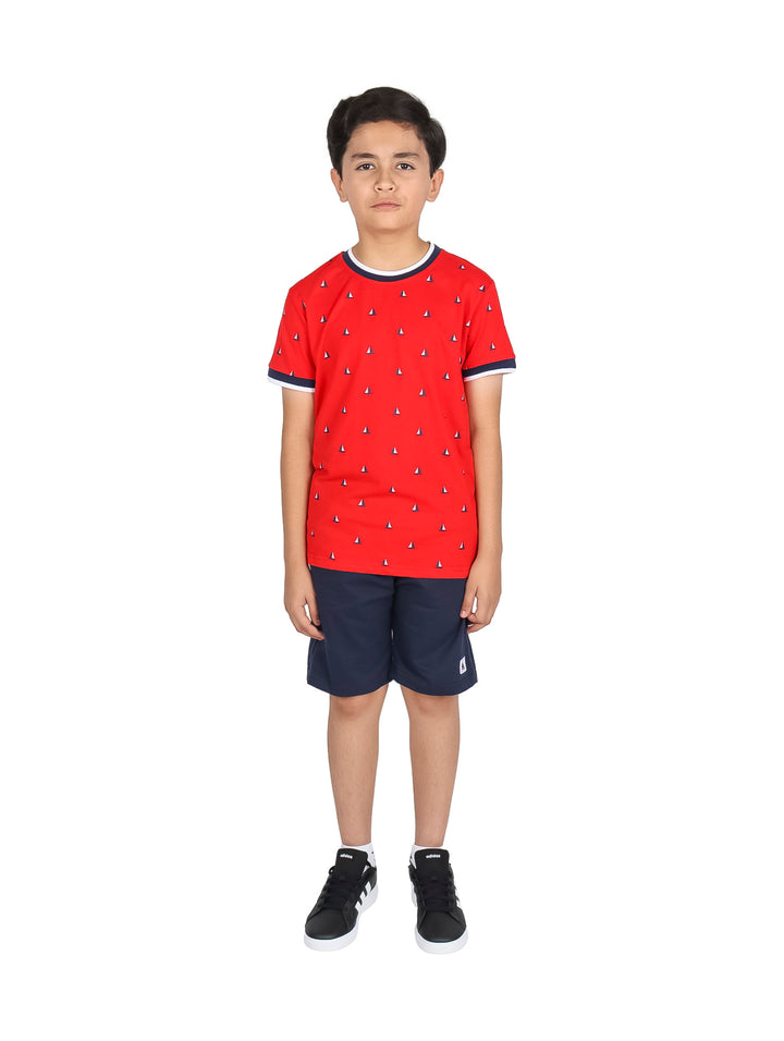 Niño vistiendo un conjunto de camiseta roja con estampado y short azul marino.