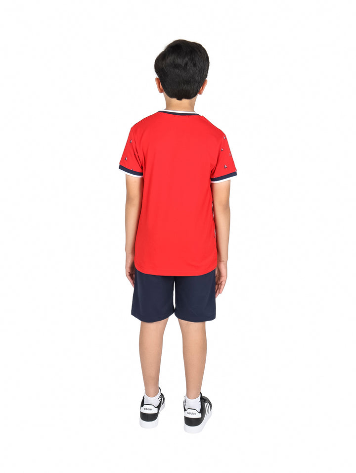 Niño vistiendo un conjunto de camiseta roja con estampado y short azul marino.