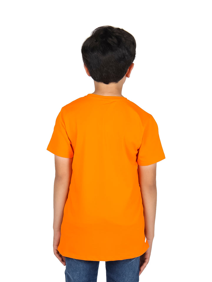 Niño vistiendo una playera naranja de manga corta con estampado gráfico frontal y pantalones mezclilla azules.