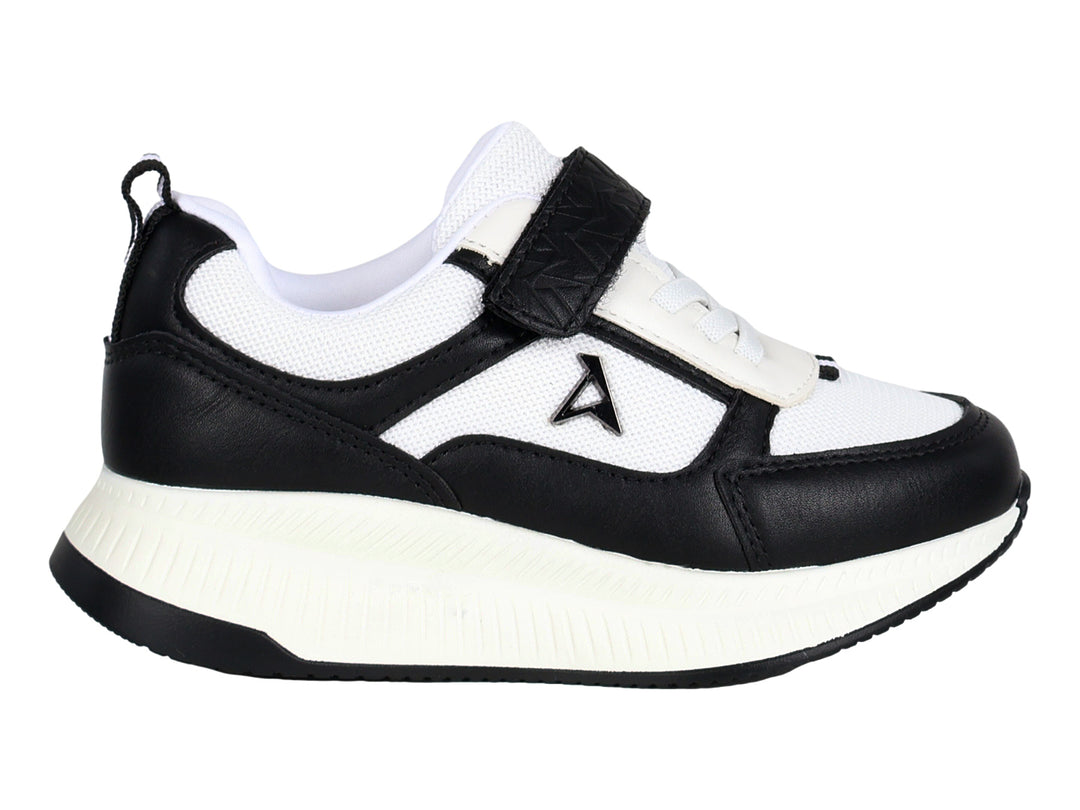 Tenis deportivos infantiles en colores blanco y negro con cierre de velcro y suela blanca.