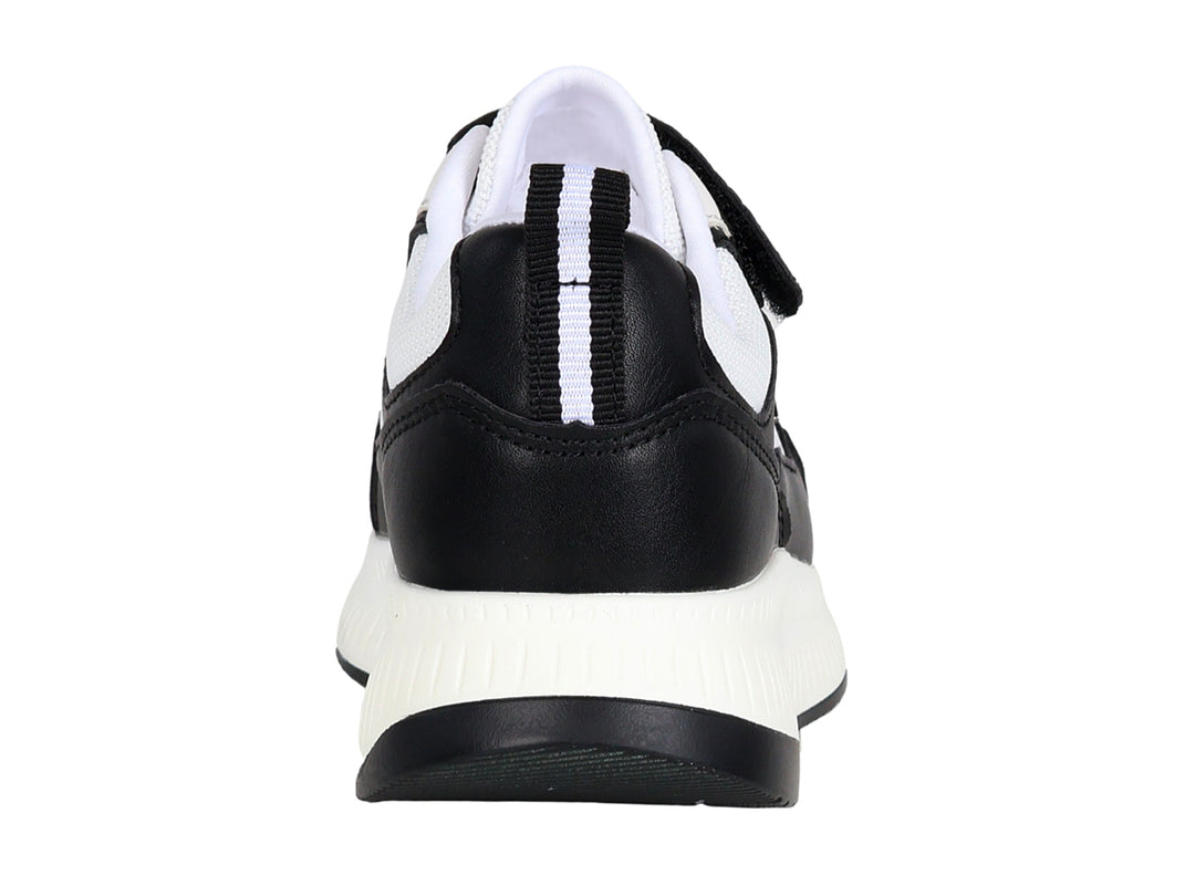 Tenis deportivos infantiles en colores blanco y negro con cierre de velcro y suela blanca.