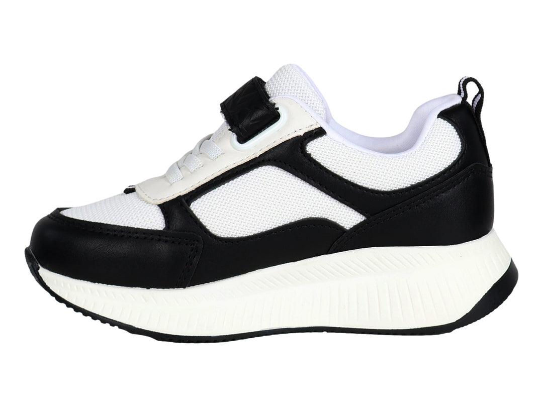 Tenis deportivos infantiles en colores blanco y negro con cierre de velcro y suela blanca.